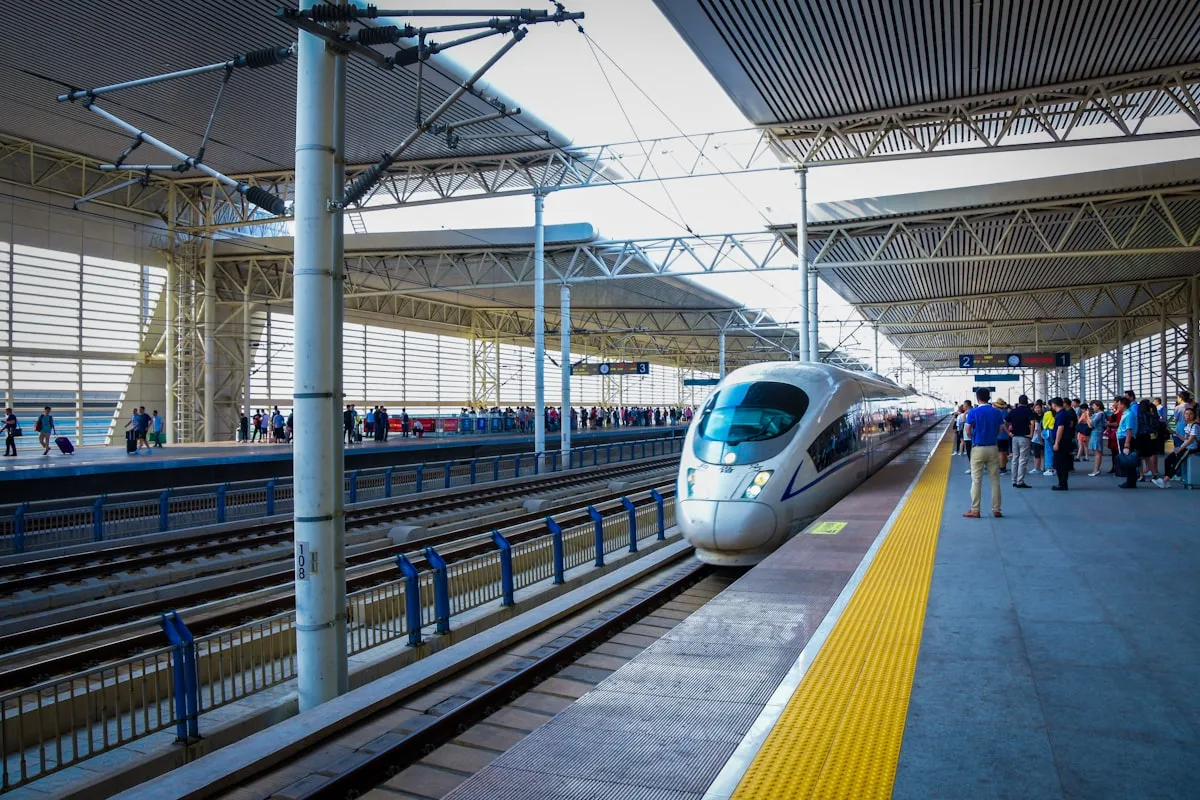 A silver high-speed train stopped at a station platform in China with passengers waiting beside it