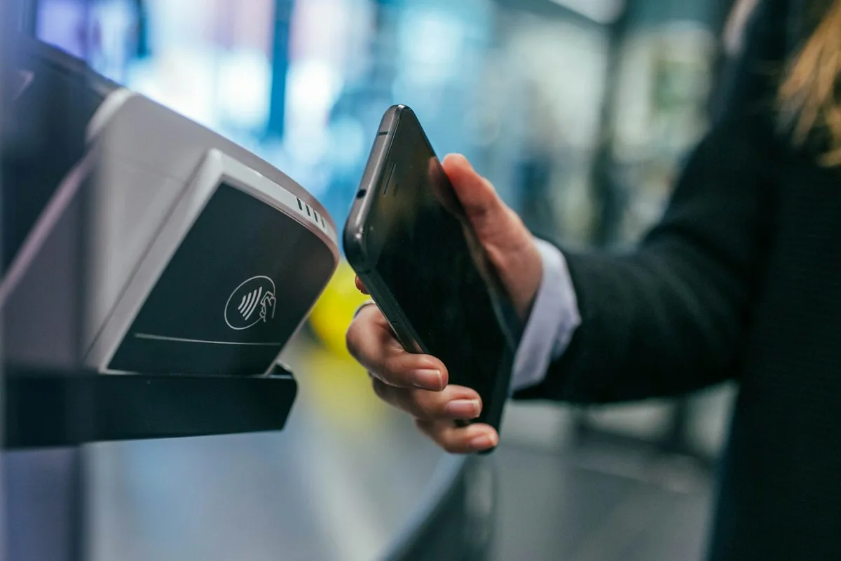 Una persona acercando un smartphone a un terminal de pago sin contacto