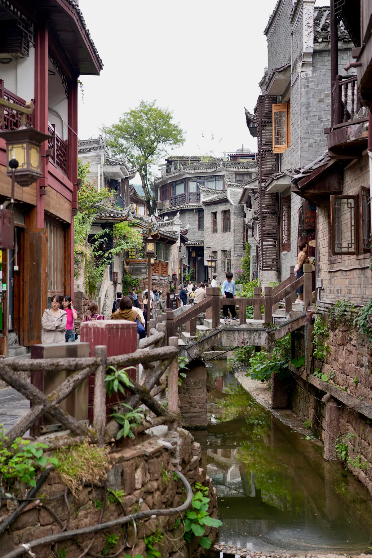 Un callejón de piedra en Fenghuang con un canal entre las casas viejas y visitantes cruzando una pasarela de madera (Foto: Lianguanlun vía Wikimedia Commons)