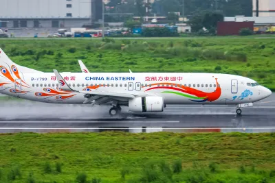 A Chinese domestic airliner on the apron at a modern terminal with a boarding bridge attached