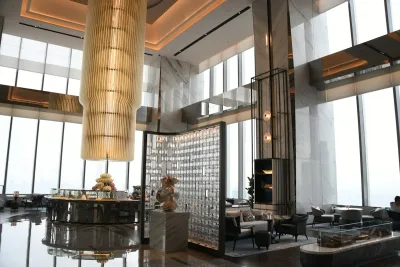Modern hotel lobby in China with a tall chandelier, marble columns and floor-to-ceiling windows overlooking the city