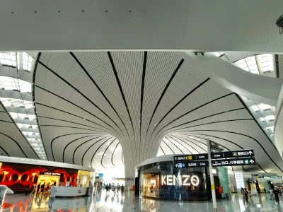 Departure hall at Beijing Daxing airport with gates signage and shops under a curved white roof