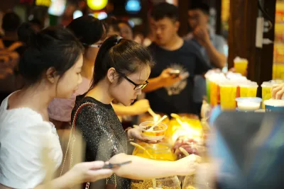 People choosing food at a busy night market stall in Chongqing