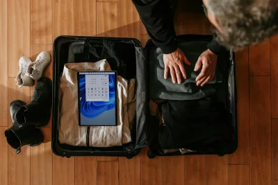 Overhead view of a person packing a suitcase with travel items