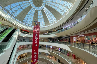 L'atrium vitré d'un centre commercial à Zhengzhou, avec ses escalators, ses balcons courbes et une longue banderole rouge suspendue dans le vide (Photo: Windmemories via Wikimedia Commons)