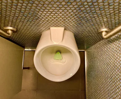 A urinal with metal grab bars in a public restroom