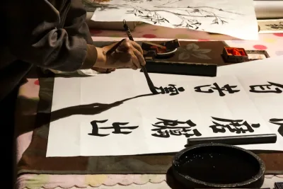 A hand writing Chinese calligraphy with brush, ink, and xuan paper