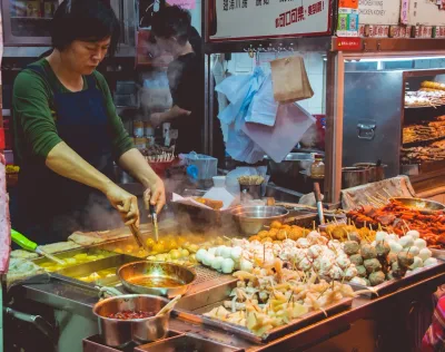 Uma mulher cozinhando comida de rua em uma barraca de mercado noturno chinês
