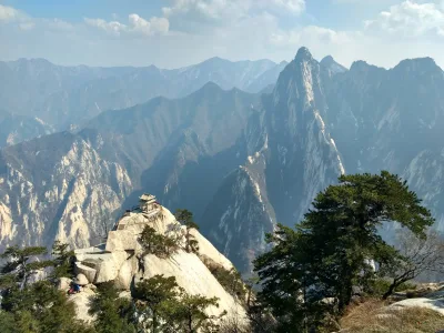 The Chess Pavilion on its rock outcrop below the East Peak ridge at Huashan, with pine trees and layered mountain ridges behind (Photo: May Wung via Wikimedia Commons)