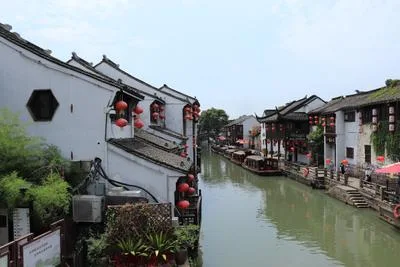 White and red boat floating on a peaceful canal in Suzhou's ancient water town