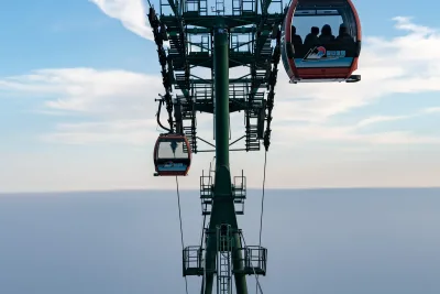 Two red cable car cabins on a green pylon above a flat sea of haze at dawn on Mount Tai