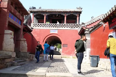 The red gatehouse of Hongmen at the start of Mount Tai's classic climbing route, with visitors walking through its stone archway
