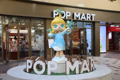 The entrance of a Pop Mart store in Zhengzhou, China, with a large Molly character statue standing in front of glass doors and the Pop Mart sign above