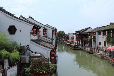 White and red boat floating on a peaceful canal in Suzhou's ancient water town