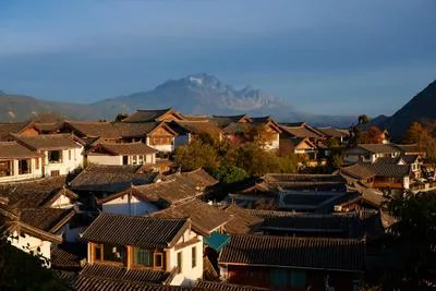 Traditional village rooftops with mountain backdrop at sunrise in Lijiang, Yunnan